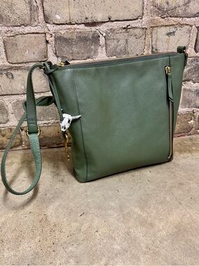 Fossil sage green and brass crossbody bag with key and cow skull charms